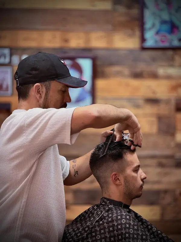 Barber cutting hair with scissors